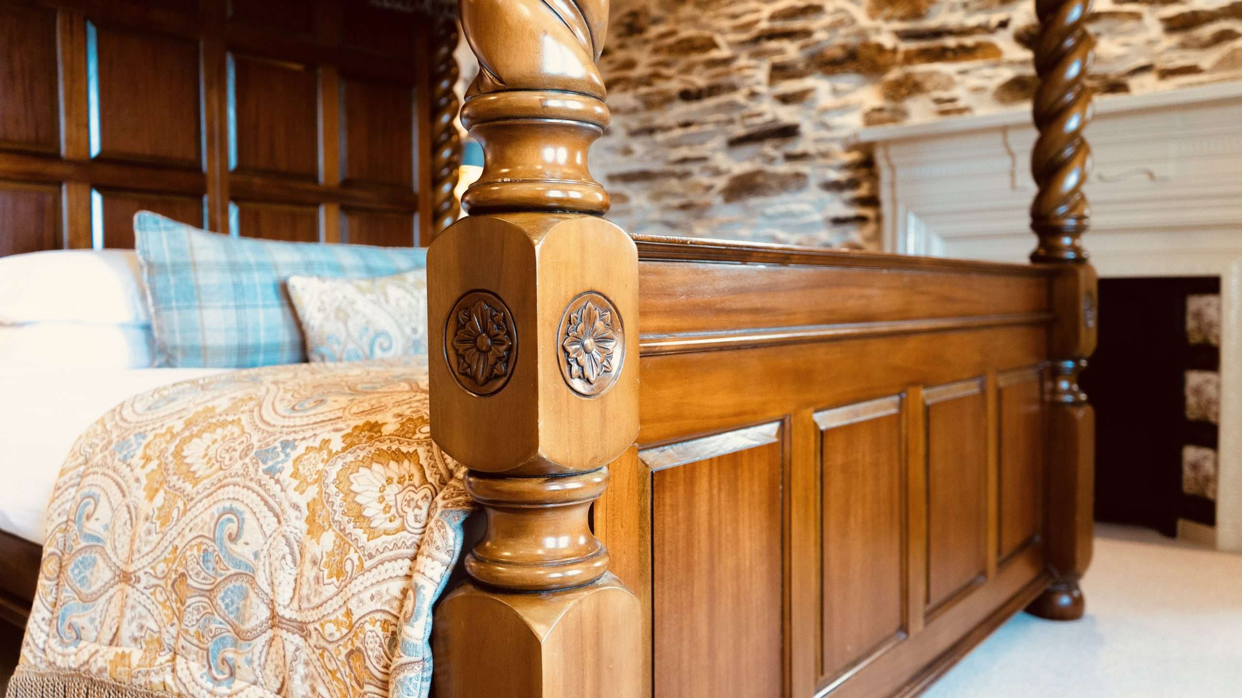 Close-up of carved wooden four-poster bed inside a luxury suite at Camelot Castle