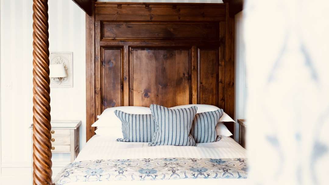 Elegant four-poster bed with soft blue accents inside Camelot Castle Hotel