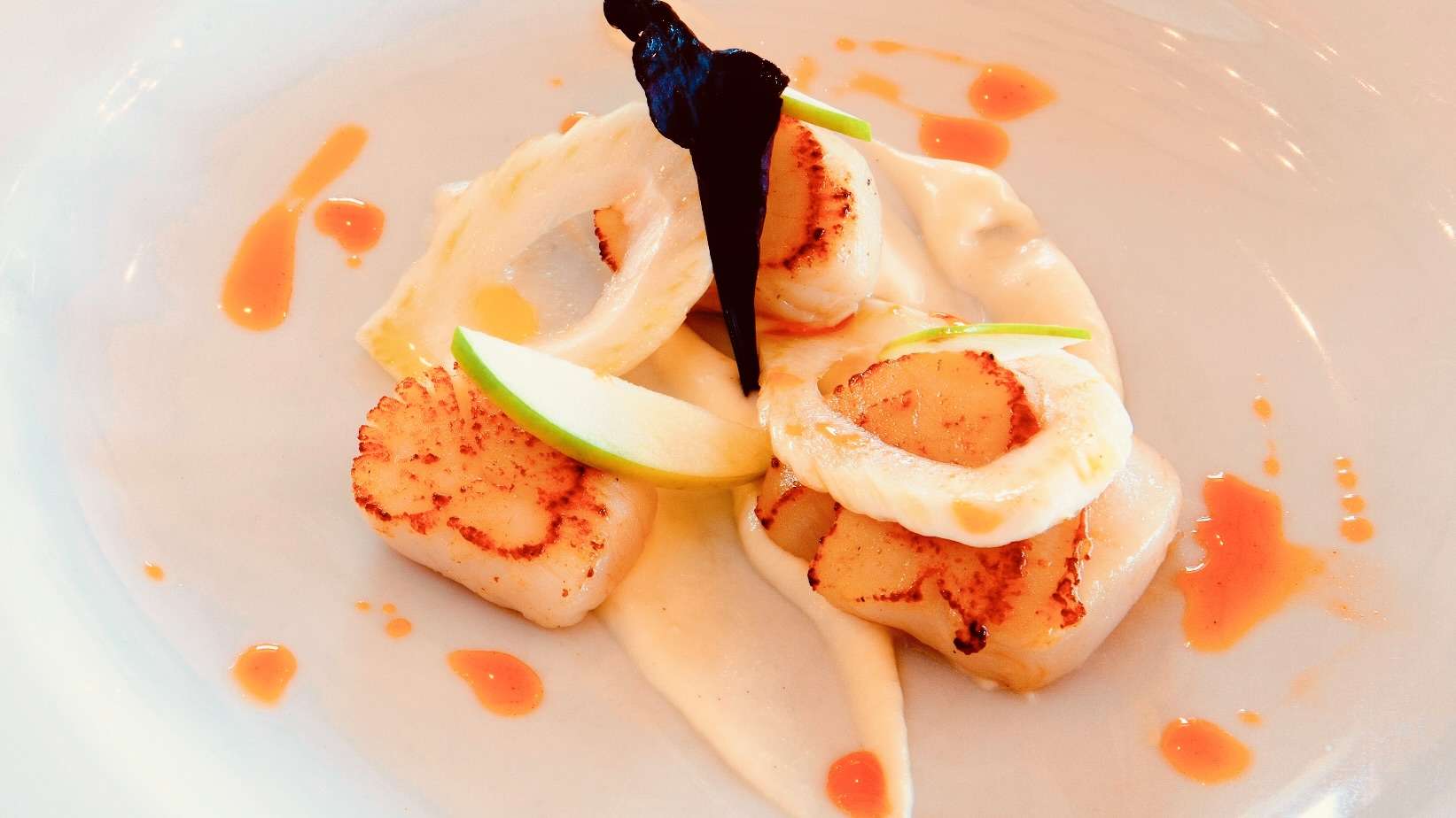 Elegant seared scallops plated with fresh apple and sauce at Camelot Castle