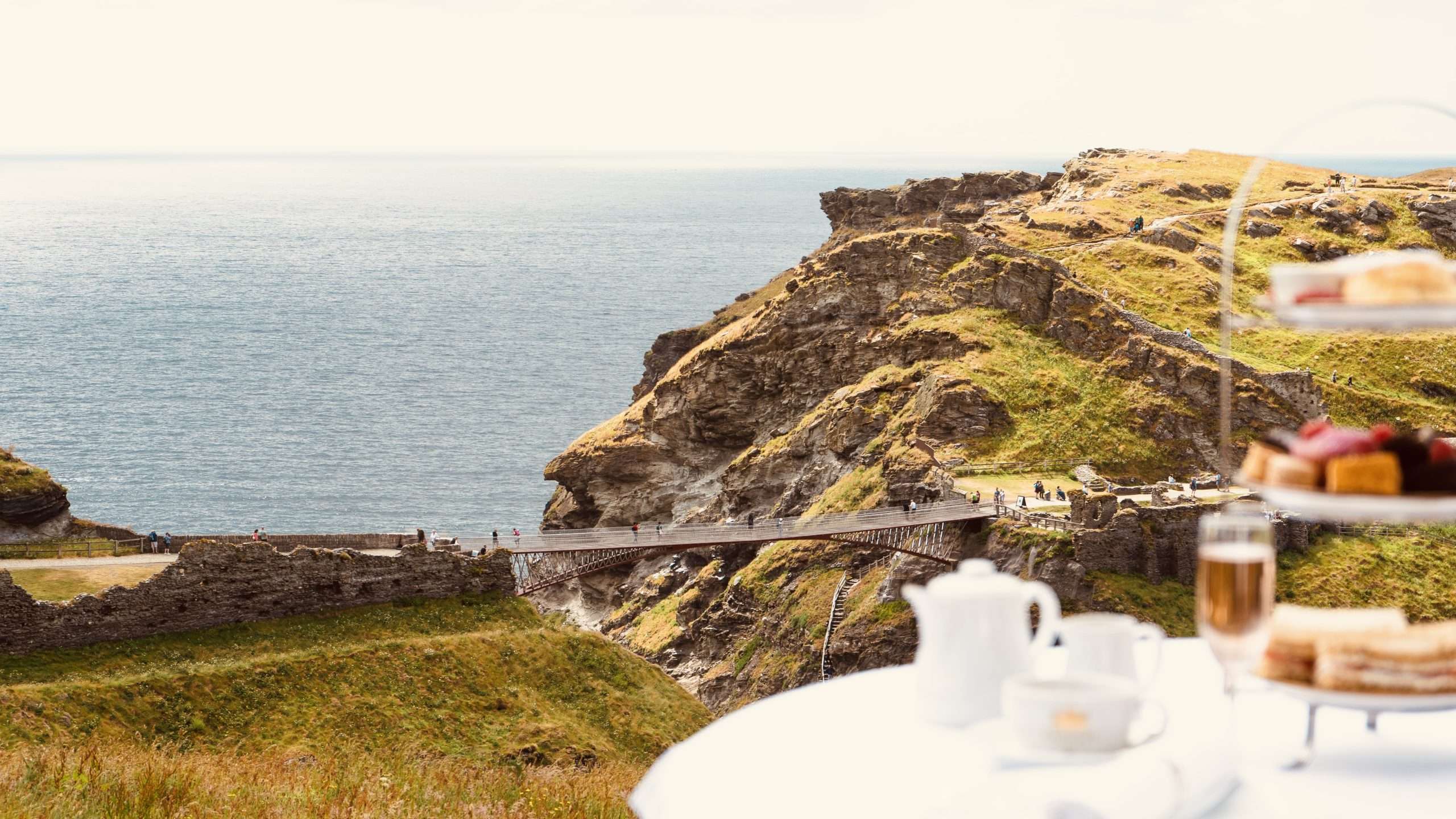 View of Tintagel Castle footbridge from Camelot Castle with afternoon tea in the foreground