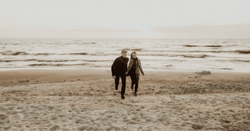 couple running in the sand in cornwall