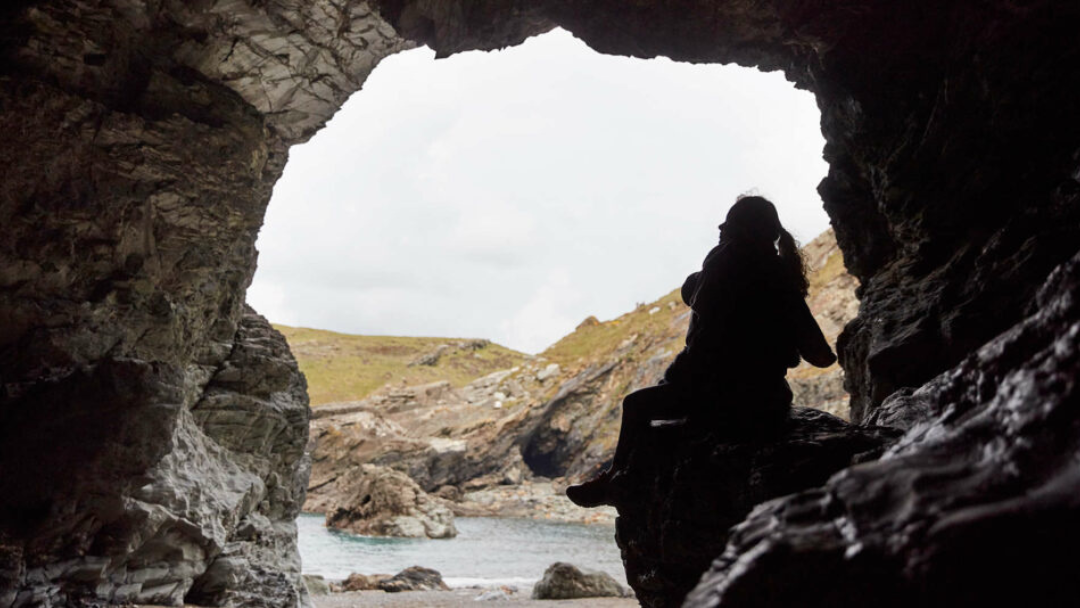 Silhouette inside a coastal cave near Tintagel with sea and cliffs beyond