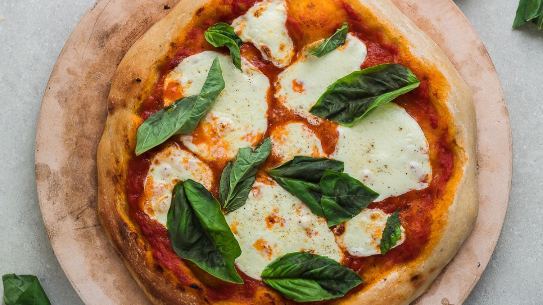 Freshly baked wood-fired pizza topped with mozzarella and basil
