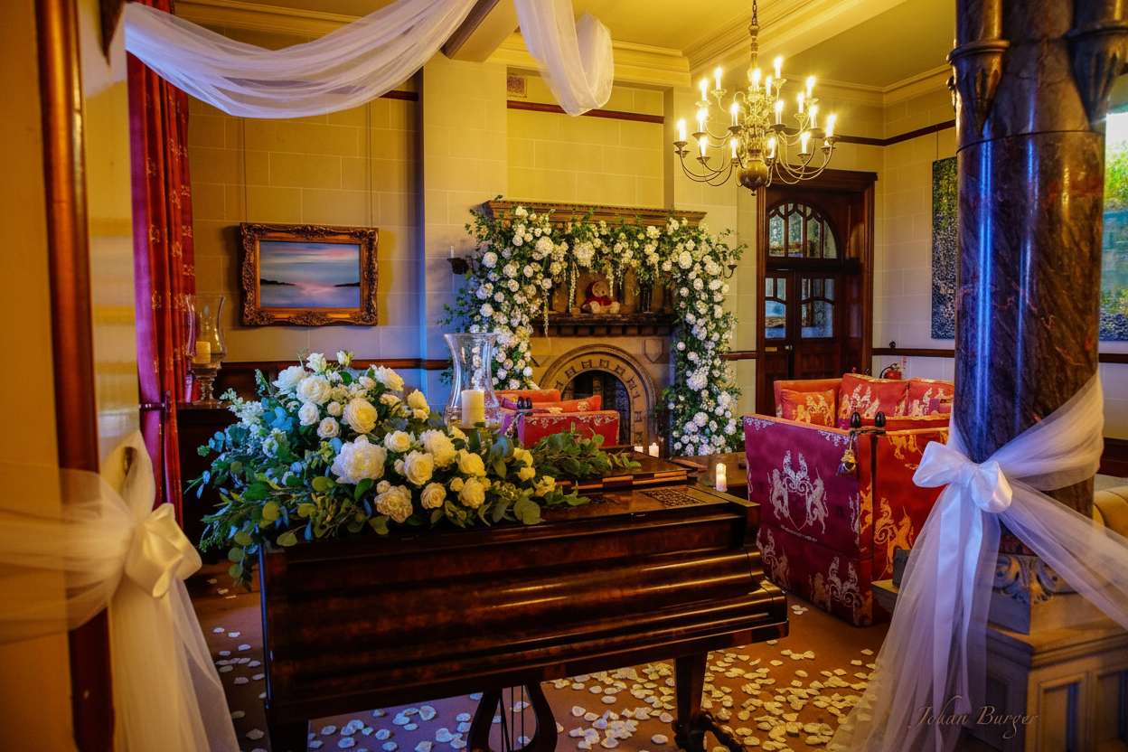 Wedding ceremony room with piano and floral arch at Camelot Castle in Tintagel Cornwall